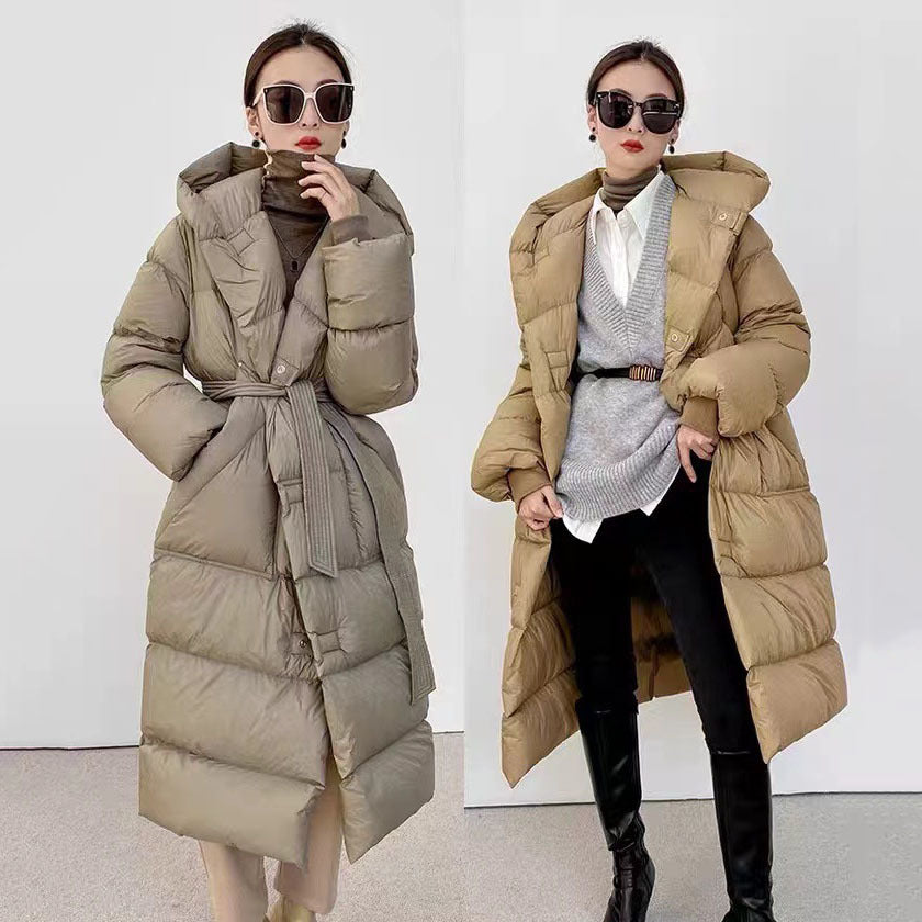Two models wearing long down jacket coats in beige and gray colors, with a fur collar, thick, and knee-length.